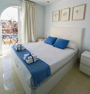 Un dormitorio con una cama con almohadas azules y una ventana. en Weisshorn Bungalow 40, en Maspalomas