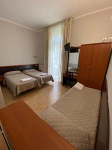 a hotel room with two beds and a desk at Hotel Atena in Milan