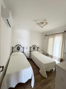 two beds in a bedroom with white walls and wooden floors at Budoni Residence Lutturai 1 in Budoni