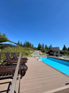 a deck with chairs and an umbrella next to a swimming pool at Foxslid in Slavske