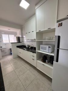 a kitchen with white cabinets and a white refrigerator at Apartamento a 50m da praia in Praia Grande