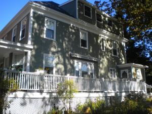 uma grande casa de madeira com uma varanda branca em Fleetwood House Bed and Breakfast em Portland