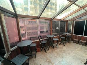 a group of tables and chairs in a room with windows at Castle of Vibes - Hostel in Rio de Janeiro