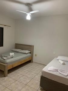 a bedroom with two beds and a ceiling fan at Casa Aconchegante em Aparecida - 600 metros da Basílica in Aparecida
