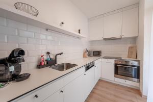a kitchen with white cabinets and a stainless steel sink at Bastion New Apartment with Parking in Košice
