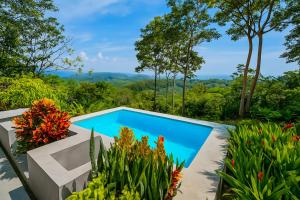 a swimming pool in a garden with flowers at Amazing Oceanview Villa with Private Pool - Fast WiFi in Ojochal