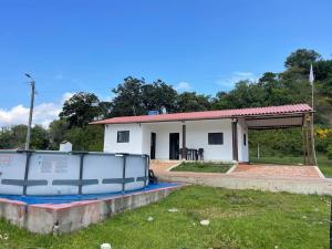 a small white house with a boat in the yard at Cabaña en Güepsa Santander in Güepsa