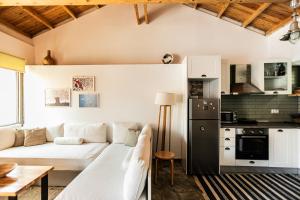 a living room with a white couch and a kitchen at Rock Solid Stone House - Chora Samothraki in Samothraki