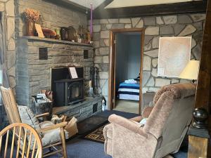 Una sala de estar con una chimenea de piedra y una silla. en Cozy Catskill Mountain Cabin, en Margaretville