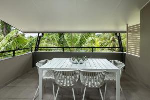 克瓦拉海滩Kewarra Beach Paradise 1BR Resort Style Apt - Pool的棕榈树阳台的白色桌椅