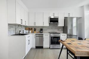 a kitchen with white cabinets and a wooden table at Luxurious 4BR with Sunny Deck Balcony in Montréal