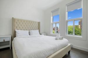 a bedroom with a large white bed with two windows at Luxurious 4BR with Sunny Deck Balcony in Montréal