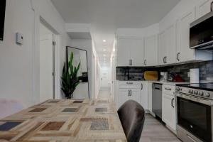 a kitchen with white cabinets and a table with chairs at Stylish 4BR Unit Near Plateau and DT MTL in Montréal