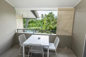 克瓦拉海滩Kewarra Beach Studio Apt with Resort Pool and BBQ的有窗户的房间里有一张白色的桌子和几把椅子