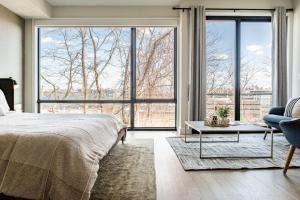 a bedroom with large windows and a bed and a chair at 4BR Townhome with NYC Views in North Bergen