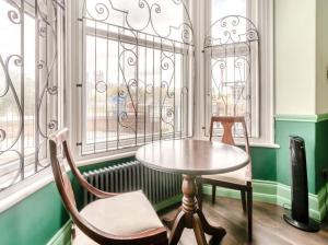 a table and chairs in a room with windows at Riverside Georgian House with Hot Tub, Sauna & Parking in Selby