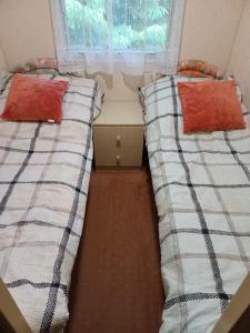two beds in a small room with a window at Domek wakacyjny in Sumowo