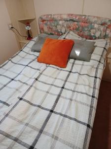a bed with an orange pillow and pillows on it at Domek wakacyjny in Sumowo +9 photos