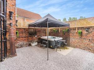 a patio with an umbrella with a table and a tub at Riverside Georgian House with Hot Tub, Sauna & Parking in Selby