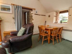 a living room with a table and a leather chair at Linhay in Bude