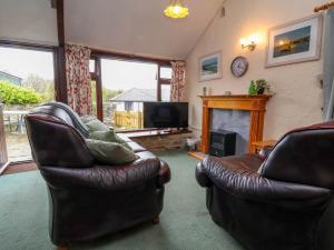 a living room with two leather chairs and a fireplace at Linhay in Bude