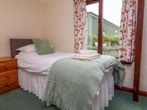 a small bedroom with a bed and a window at Linhay in Bude +14 photos