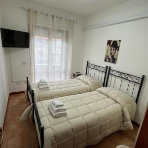 a bedroom with two beds and a flat screen tv at Appartamento Antonietta- in Santa Maria degli Angeli