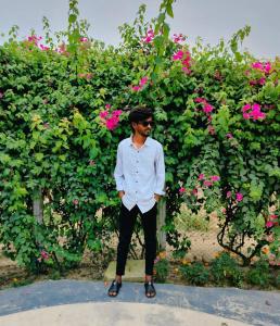 un hombre parado frente a un arbusto con flores rosas en Jurain Dhaka, en Dhaka