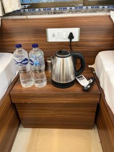 KhātuHotel Shri Raghuvansh的茶壶和床头柜上的2瓶水