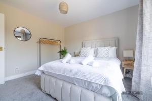 a white bedroom with a large white bed with white pillows at Belfast Quarters Riverside in Belfast
