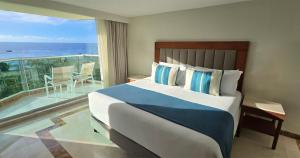 a bedroom with a bed and a balcony with the ocean at Grand Park Royal Cozumel - All Inclusive in Cozumel