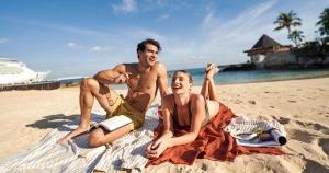 a man and a woman sitting on the beach at Grand Park Royal Cozumel - All Inclusive in Cozumel