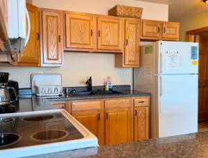 a kitchen with wooden cabinets and a white refrigerator at Bull Frog Bay #2 - Downtown Minocqua in Minocqua