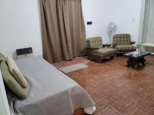 a bedroom with a bed and two chairs and a table at Casona Villa General Savio in Villa General Savio