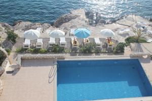 einen Pool mit Stühlen und Sonnenschirmen am Meer in der Unterkunft Villa Simpatia in Primošten