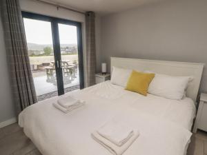 Un dormitorio con una cama blanca con una ventana grande. en The Willows, en Newport