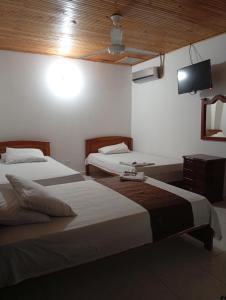 two beds in a room with a tv on the wall at Hotel kerana moon in Puerto Boyacá +9 photos