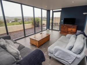 sala de estar con 2 sofás, TV y ventanas en The Willows, en Newport