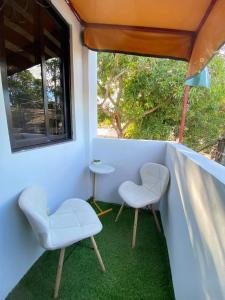 two chairs and a table on a balcony with a window at Cabuhat Duco Lodge 31 in Tanza