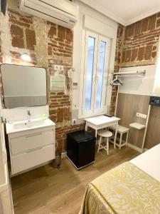 a bedroom with a bed and a tv on a brick wall at Hostal Madrid in Madrid