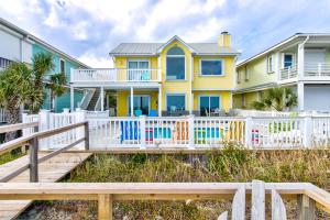 a yellow house with a white fence at Dolphin Run by Carolina Beach Realty in Kure Beach