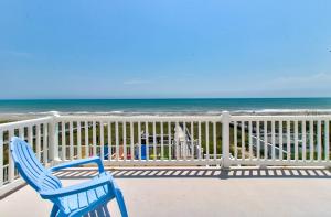 a blue chair sitting on a balcony overlooking the ocean at Dolphin Run by Carolina Beach Realty in Kure Beach +34 photos