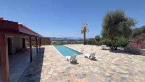 a swimming pool with two lounge chairs next to a house at Gümüşlük Ümit Villa in Bodrum City