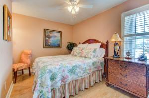 a bedroom with a bed and a dresser and a window at Driftwood Villa 101 by Carolina Beach Realty in Carolina Beach