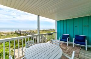weranda ze stołem i krzesłami oraz plaża w obiekcie Dunes I A1 Seas The Day by Carolina Beach Realty w mieście Carolina Beach