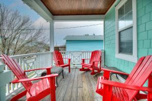 a porch with red rocking chairs on a house at Elanora by Carolina Beach Realty in Kure Beach