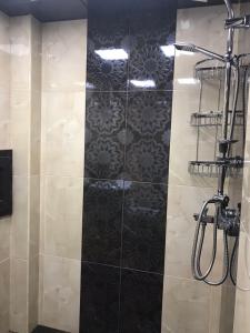a bathroom with a shower with a black tile wall at Хорошем месте находится, улица Иззет Небиев 6-22 in Baku