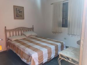 a bedroom with a bed and a table and a window at Encanto Mada´s Itamambuca in Ubatuba