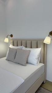 a bed with white pillows and two lights on it at Tafra apartmani Igalo in Igalo