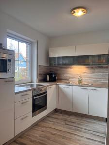 eine Küche mit weißen Schränken und Geräten aus Edelstahl in der Unterkunft Haus Boddenruh Ferienwohnung Holz in Wiek auf Rügen 